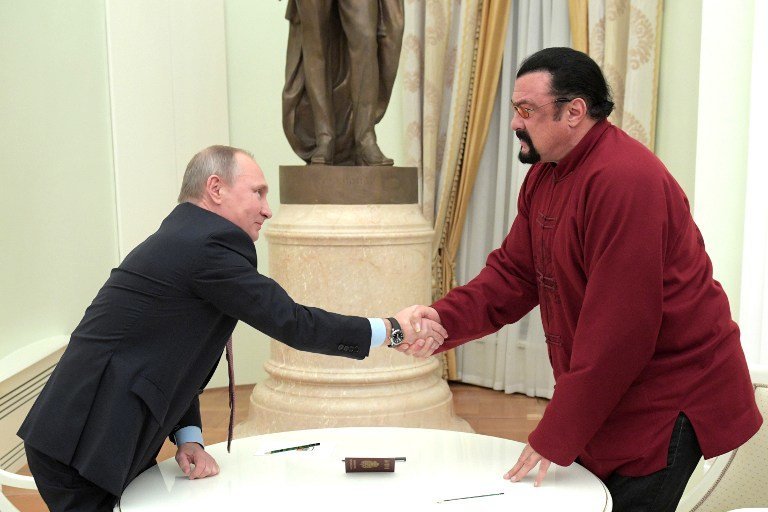 Russian President Vladimir Putin (L) shakes hands with US action hero actor Steven Seagal after presenting a Russian passport to him during a meeting at the Kremlin in Moscow on November 25, 2016. / AFP PHOTO / SPUTNIK / Alexey DRUZHININ