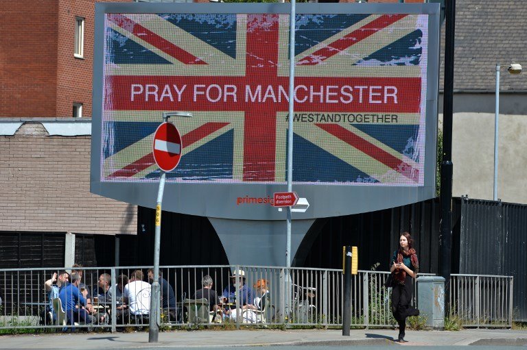 A woman walks past an electronic advertising board displaying a Union flag and the words "Pray For Manchester", close to the Manchester Arena in Manchester, northwest England on May 23, 2017, following a deadly terror attack at an Ariana Grande concert at the Manchester Arena on May 22.
Twenty two people have been killed and dozens injured in Britain's deadliest terror attack in over a decade after a suspected suicide bomber targeted fans leaving a concert of US singer Ariana Grande in Manchester. / AFP PHOTO / Ben Stansall
