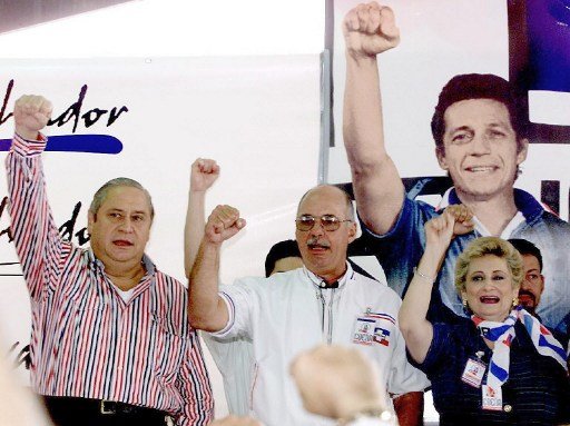 The leaders of the government party, the National Republican Alliance, ARENA), Armando calderon Sol (L), Alfredo Cristiani (C), and ex-presidents of the republic, Milena de Escalon (R) support their party, 19 May 2000.Los lideres del partido de gobierno Alianza Republicana Nacionalista (ARENA) Armando Calderon Sol (I), Alfredo Cristiani (C), ambos ex-presidentes de la republica y Milena de Escalon (D) cantan el himno de su partido, el 19 de Mayo de 2000, bajo la imagen del fallecido ex- mayor del ejercito Roberto D'Aubuisson durante la apertura de un congreso partidista en San Salvador, El Salvador. El Partido ARENA realiza su congreso tras la derrota sufrida en los pasados comicios legislativos y municipales. (ELECTRONIC IMAGE) AFP PHOTO / Yuri CORTEZ / AFP PHOTO / YURI CORTEZ