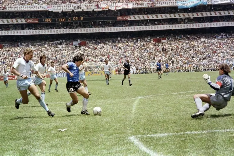 <p>Diego Maradona enfrenta al portero ingl&eacute;s Peter Shilton (D) para marcar un gol antol&oacute;gico en la historia de los mundiales, en partido semifinal de la Copa del Mundo de M&eacute;xico-1986, el 22 de junio en Ciudad de M&eacute;xico</p>