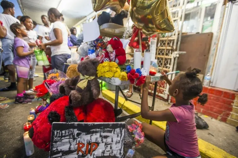 <p>Una ni&ntilde;a escribe un mensaje frente a la tienda en cuyo estacionamiento fue abatido Alton Sterling, el 6 de julio de 2016 en Baton Rouge, Luisiana</p>