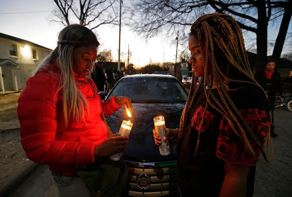 Destiny Brown, left, and Bonnie King light candles during a vigil near the scene of a fatal shooting in Raleigh, N.C., Monday, Feb. 29, 2016. Authorities say that a police officer shot and killed a man while trying to make an arrest for a felony drug charge. (AP Photo/Gerry Broome)