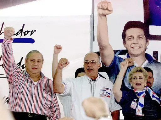 The leaders of the government party, the National Republican Alliance, ARENA), Armando calderon Sol (L), Alfredo Cristiani (C), and ex-presidents of the republic, Milena de Escalon (R) support their party, 19 May 2000.
Los lideres del partido de gobierno Alianza Republicana Nacionalista (ARENA) Armando Calderon Sol (I), Alfredo Cristiani (C), ambos ex-presidentes de la republica y Milena de Escalon (D) cantan el himno de su partido, el 19 de Mayo de 2000, bajo la imagen del fallecido ex- mayor del ejercito Roberto D'Aubuisson durante la apertura de un congreso partidista en San Salvador, El Salvador. El Partido ARENA realiza su congreso tras la derrota sufrida en los pasados comicios legislativos y municipales.  (ELECTRONIC IMAGE)    AFP PHOTO / Yuri CORTEZ / AFP PHOTO / YURI CORTEZ
