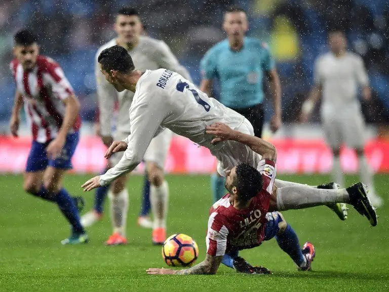 Real Madrid's Portuguese forward Cristiano Ronaldo (top) falls over Sporting Gijon's defender Lillo Castellano during the Spanish league football match Real Madrid CF vs Real Sporting de Gijon at the Santiago Bernabeu stadium in Madrid on November 26, 2016. / AFP PHOTO / JAVIER SORIANO