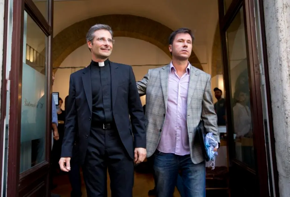 Monsignor Krzysztof Charamsa, left, and his boyfriend Eduard, surname not given, pose for a photo as they leave a restaurant after a press conference in downtown Rome, Saturday Oct. 3, 2015. Vatican on Saturday fired a monsignor who came out as gay on the eve of a big meeting of the world's bishops to discuss church outreach to gays, divorcees and more traditional Catholic families. (AP Photo/Alessandra Tarantino) 