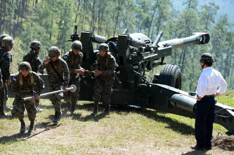 Honduran President Juan Orlando Hernandez (R) prepares to fire a 155mm M 198 howitzer during the Artilleryman Day in Zambrano, 30 km north of Tegucigalpa, on November 29, 2016. / AFP PHOTO / ORLANDO SIERRA