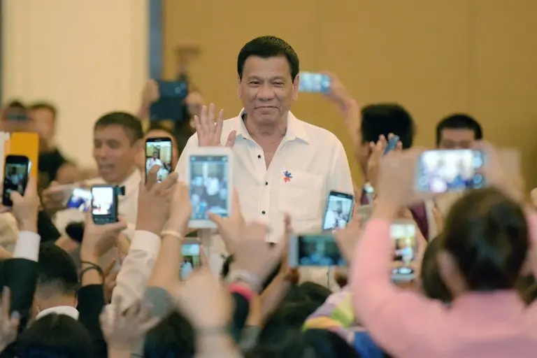 Philippine President Rodrigo Duterte greets members of the Filipino community as he arrives in the Cambodian capital Phnom Penh on December 13, 2016. 
Duterte is on a two-day state visit to Cambodia. / AFP PHOTO / TANG CHHIN SOTHY