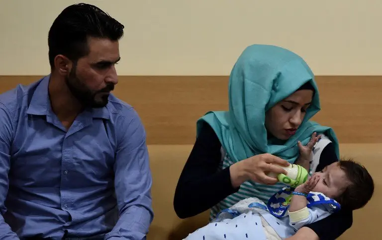 Iraqi mother Gufran Ali (C) is watched by her husband Sarwed Ahmed Nadar as she holds their eight month old son Karam during a press conference at a hospital in Noida on April 14, 2017.
A baby born with eight limbs, including two protruding from his stomach, has undergone surgery in India to successfully remove the extra arms and legs, in an operation being hailed as a world first. Seven-month-old Karam was born in Iraq with an extremely rare condition where a conjoined twin did not fully form and was partially absorbed, resulting in the additional limbs.
 / AFP PHOTO / Money SHARMA
