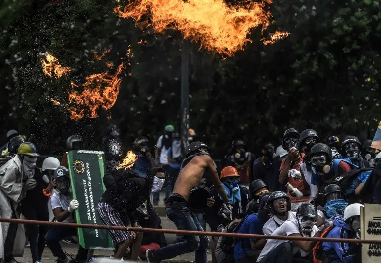 Anti-government protesters blocking the Francisco Fajardo highway in Caracas clash with riot police during a demonstration against Venezuelan President Nicolas Maduro on May 27, 2017.
Demonstrations that got underway in late March have claimed the lives of 58 people, as opposition leaders seek to ramp up pressure on Venezuela's leftist president, whose already-low popularity has cratered amid ongoing shortages of food and medicines, among other economic woes. / AFP PHOTO / JUAN BARRETO