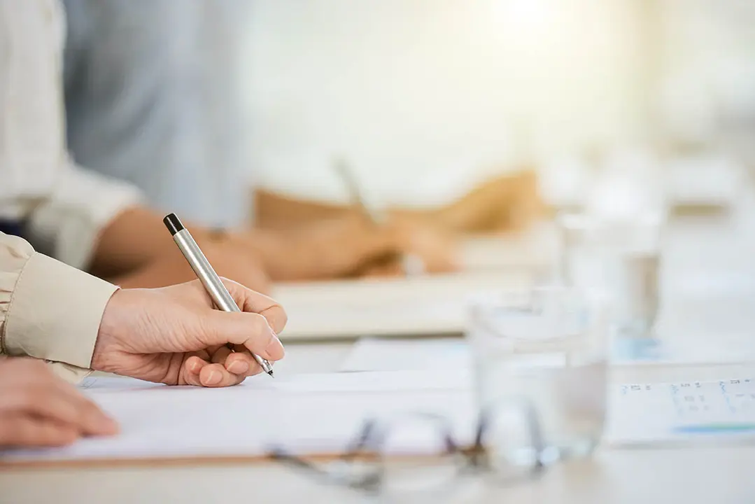 Hand of business lady signing agreement at meeting