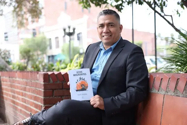 Soudi Jiménez muestra su libro sentado en la emblemática Plaza Olvera en el corazón de la ciudad de Los Ángeles