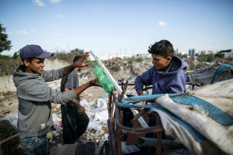 <p>Dos niños palestinos, Karam al Zaaneen (dcha.) y su hermano Mustafá, recogen basura en Bait Hanun, en el norte de la Franja de Gaza, el 18 de mayo de 2016</p>