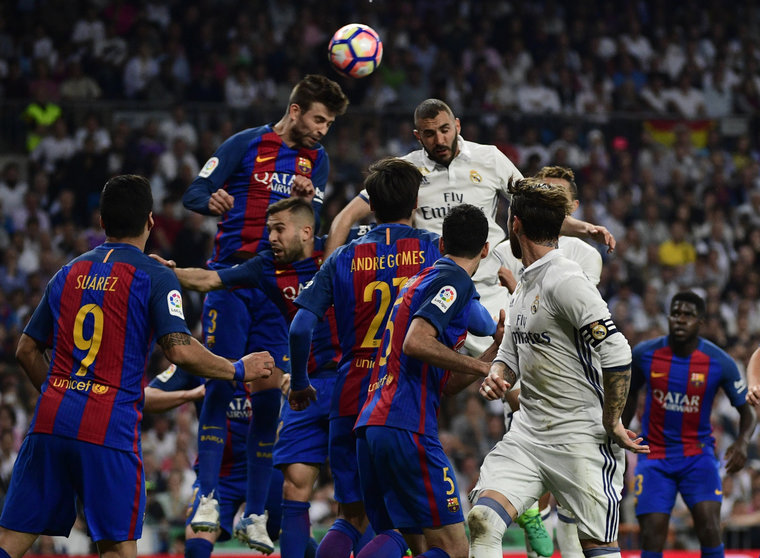 Barcelona's defender Gerard Pique (top L) heads the ball with Real Madrid's French forward Karim Benzema (top R) during the Spanish league football match Real Madrid CF vs FC Barcelona at the Santiago Bernabeu stadium in Madrid on April 23, 2017. / AFP PHOTO / PIERRE-PHILIPPE MARCOU