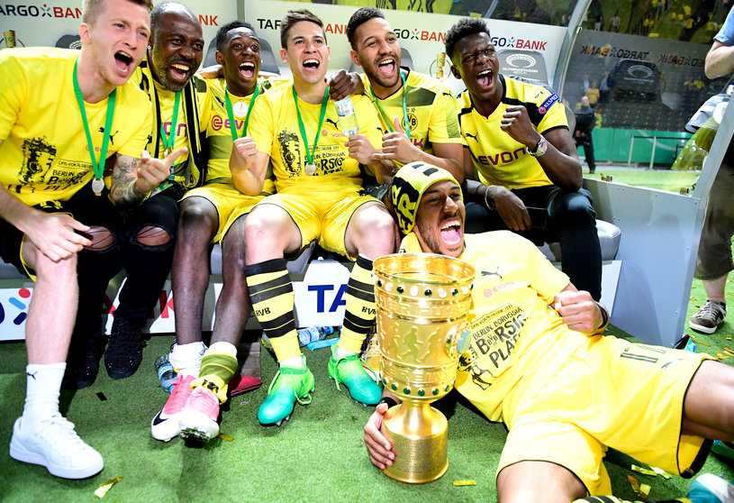 Dortmund's Gabonese forward Pierre-Emerick Aubameyang (front) and teamates celebrate with the trophy after victory during the German Cup (DFB Pokal) final football match Eintracht Frankfurt v BVB Borussia Dortmund at the Olympic stadium in Berlin on May 27, 2017. / AFP PHOTO / Tobias SCHWARZ / RESTRICTIONS: ACCORDING TO DFB RULES IMAGE SEQUENCES TO SIMULATE VIDEO IS NOT ALLOWED DURING MATCH TIME. MOBILE (MMS) USE IS NOT ALLOWED DURING AND FOR FURTHER TWO HOURS AFTER THE MATCH. == RESTRICTED TO EDITORIAL USE == FOR MORE INFORMATION CONTACT DFB DIRECTLY AT +49 69 67880

 / 