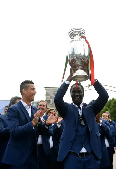 <p>Éder sostiene la copa mientras su compañero Cristiano Ronaldo aplaude sonriente, este lunes 11 de julio en Marcoussis (cerca de París), lugar de concentración de Portugal durante todo el campeonato</p>