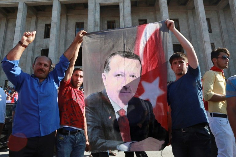 Varios hombres exhiben una imagen de Recep Tayyip Erdogan frente a la sede del Parlamento turco, reunido en sesión extraordinaria tras el intento de golpe militar, este sábado 16 de julio en Ankara
