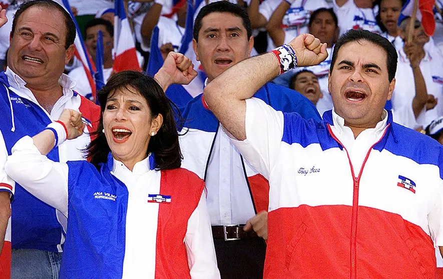 Antonio Saca (R) and Ana Vilma de Escobar presidential and vice-presidential candidates for the Alianza Republicana Nacionalista (ARENA) sing their party's anthem during a closing campaing rally at the Jorge "El Magico" Gonzalez stadium in San Salvador March 14, 2004. Presidential elections will be held on March 21st.       AFP PHOTO/Roberto ESCOBAR / AFP PHOTO / ROBERTO ESCOBAR