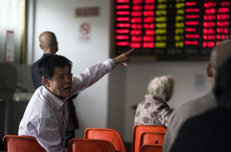 An investor gestures in front of the stock price movements on a screen at a securities company in Shanghai on November 7, 2016. / AFP PHOTO / JOHANNES EISELE