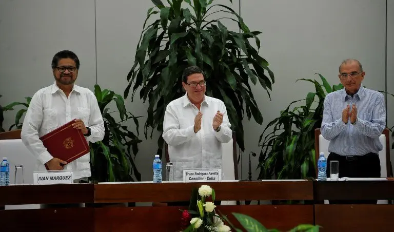 Cuban Foreign Affairs Minister Bruno Rodriguez Parrilla (C) appplauds after FARC-EP leftist guerrilla commander Ivan Marquez (L) and the head of the Colombian delegation for peace talks Humberto de la Calle (R) signed a new peace agreement in Havana, on November 12, 2016.
Colombia's government and Marxist FARC rebels on Saturday announced a new peace deal to end 52 years of civil war, after voters rejected a prior peace accord in a referendum. / AFP PHOTO / YAMIL LAGE