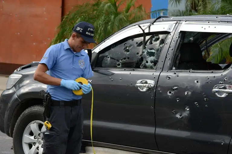 A police officer works beside the bullet-riddled truck the administrator of San Pedro Sula's penitentiary Hugo Hernandez was traveling in when it was attacked by gunmen in a place 180 km north of Tegucigalpa, on November 14, 2016.
Two other people who were in the vehicle also died in the attack carried out with assault rifles along a during which more than 300 shots were fired. / AFP PHOTO / ORLANDO SIERRA