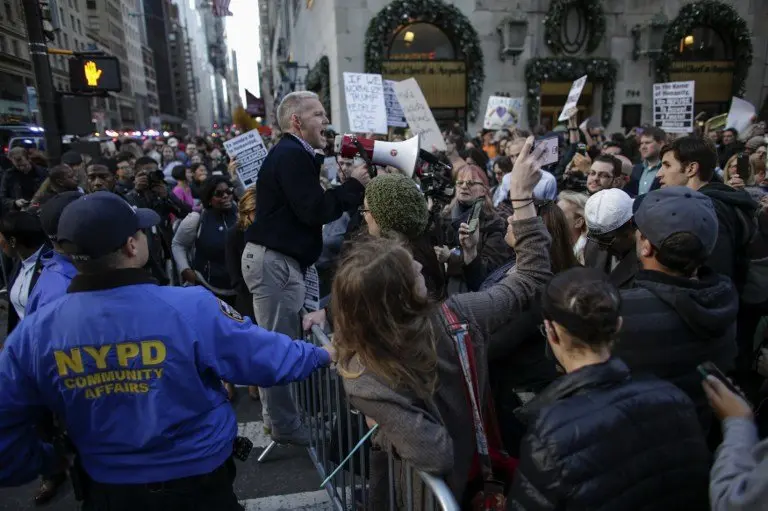 New York Councilman Jimmy Van Bramer (C) shouts slogans as he attends a protest against US President-elect Donald in front of Trump Tower on November 19, 2016 in New York. / AFP PHOTO / KENA BETANCUR