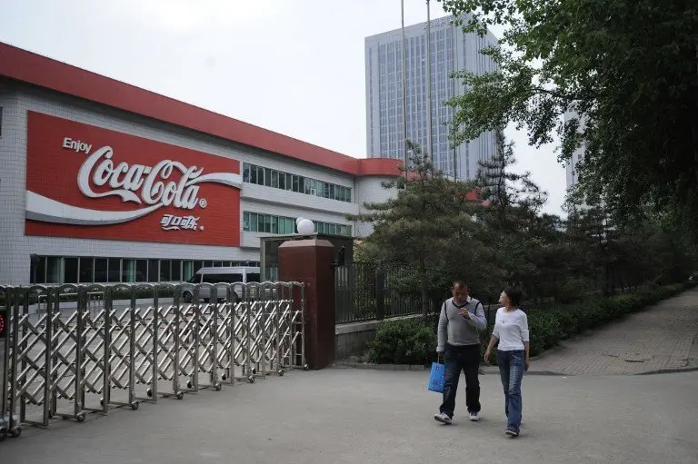 Two workers walk pass the gate of the Coca-Cola Shanxi Beverages Company in Taiyuan, northeast China's Shanxi province on April 30, 2012. Coca-Cola has been ordered to temporarily halt production at a bottling plant in northern China after media reports of chlorine in its products, according to an April 28, 2012 government statement. CHINA OUT AFP PHOTO / AFP PHOTO / STR