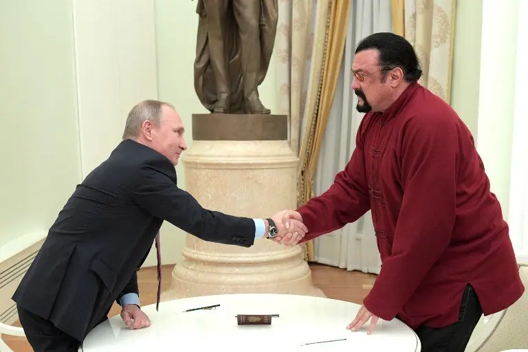 Russian President Vladimir Putin (L) shakes hands with US action hero actor Steven Seagal after presenting a Russian passport to him during a meeting at the Kremlin in Moscow on November 25, 2016. / AFP PHOTO / SPUTNIK / Alexey DRUZHININ