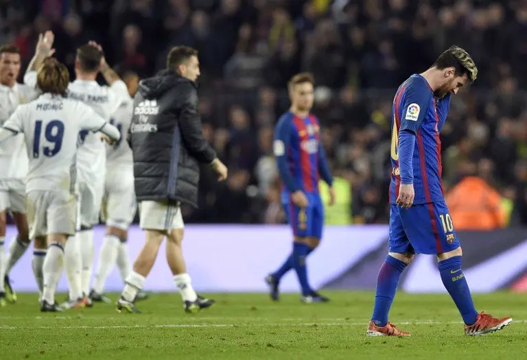 Barcelona's Argentinian forward Lionel Messi (R) walks on the pitch as Real Madrid players celebrate during the Spanish league football match FC Barcelona vs Real Madrid CF at the Camp Nou stadium in Barcelona on December 3, 2016. / AFP PHOTO / LLUIS GENE