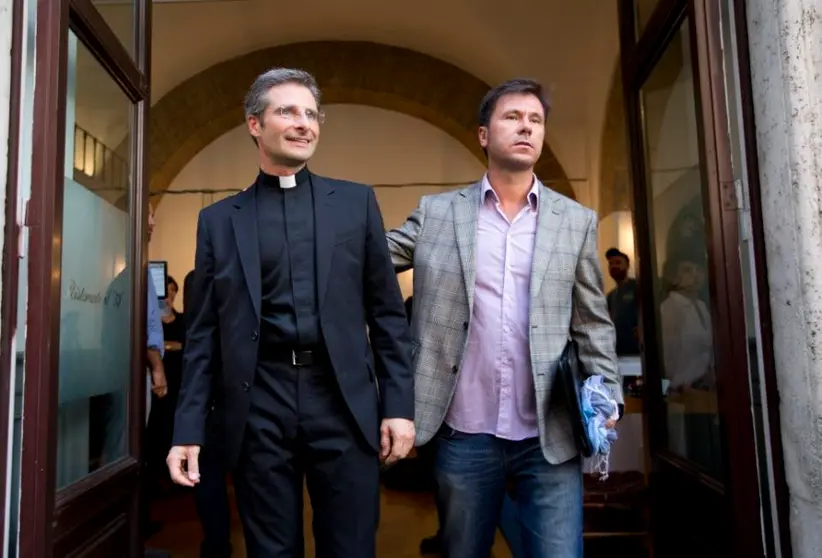 Monsignor Krzysztof Charamsa, left, and his boyfriend Eduard, surname not given, pose for a photo as they leave a restaurant after a press conference in downtown Rome, Saturday Oct. 3, 2015. Vatican on Saturday fired a monsignor who came out as gay on the eve of a big meeting of the world's bishops to discuss church outreach to gays, divorcees and more traditional Catholic families. (AP Photo/Alessandra Tarantino)