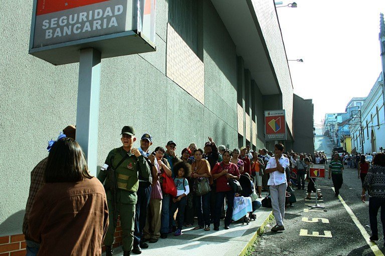 People queue up outside a bank in San Cristobal in an attempt to deposit money, on December 13, 2016. 
Venezuelan President Nicolas Maduro ordered on December 12 the border with Colombia sealed for 72 hours, accusing US-backed "mafias" of conspiring to destabilize his country's economy by hoarding bank notes. The closure came a day after Maduro signed an emergency decree removing Venezuela's largest bank note, the 100 bolivar bill, from circulation because of what he called a Washington-sponsored plot against his country's troubled economy. / AFP PHOTO / George CASTELLANOS