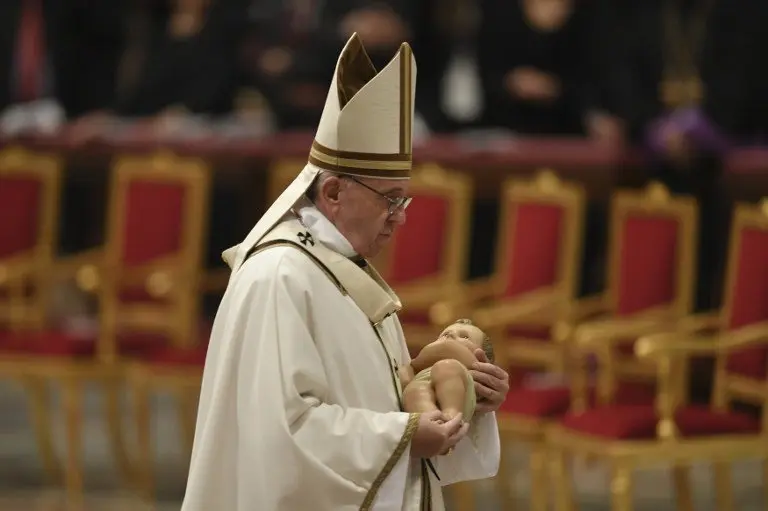 Pope Francis carries the statue of baby Jesus during a mass on Christmas eve marking the birth of Jesus Christ on December 24, 2016 at St Peter's basilica in Vatican / AFP PHOTO / ANDREAS SOLARO