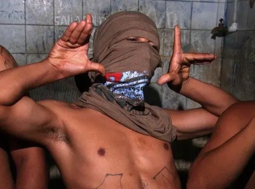 A member of the "Mara 18" juvenile gang makes signs used by the initiated to recognize each other while kept 24 April, 2007 in a cell of the police station of Ilopango, El Salvador, after having been arrested in a raid. Some 200 police members from Central America, Mexico and the US are meeting from Tuesday to Thursday in El Salvador to exchange experiences on the fight against gangs. AFP PHOTO/Jose CABEZAS / AFP PHOTO / Jose CABEZAS