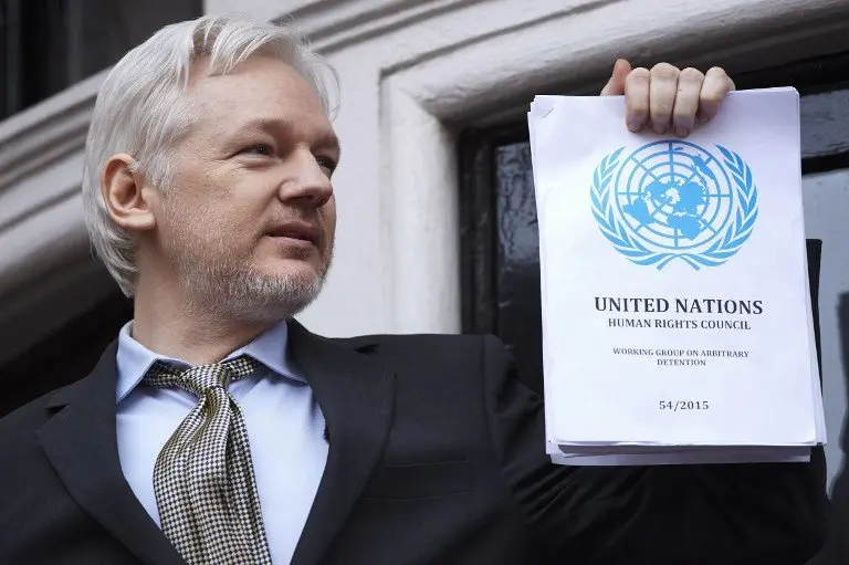 WikiLeaks founder Julian Assange addresses the media holding a printed report of the judgement of the UN's Working Group on Arbitrary Detention on his case from the balcony of the Ecuadorian embassy in central London on February 5, 2016.
During a press conference on February 5 Julian Assange, speaking via video-link, called for Britain and Sweden to "implement" a UN panel finding saying that he should be able to walk free from Ecuador's embassy, where he has lived in self-imposed confinement since 2012. / AFP PHOTO / NIKLAS HALLE'N