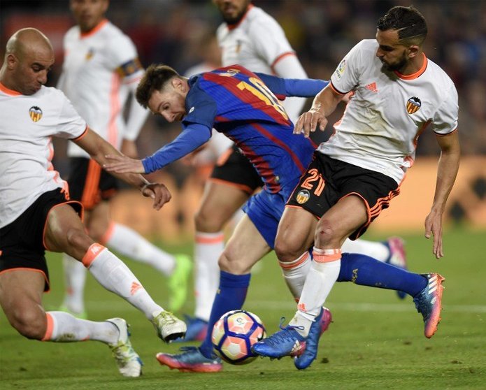 Barcelona's Argentinian forward Lionel Messi (C) vies with Valencia's defender Martin Montoya (R) and Valencia's Tunisian defender Aymen Abdennour (L)  during the Spanish league football match FC Barcelona vs Valencia CF at the Camp Nou stadium in Barcelona on March 19, 2017. / AFP PHOTO / LLUIS GENE