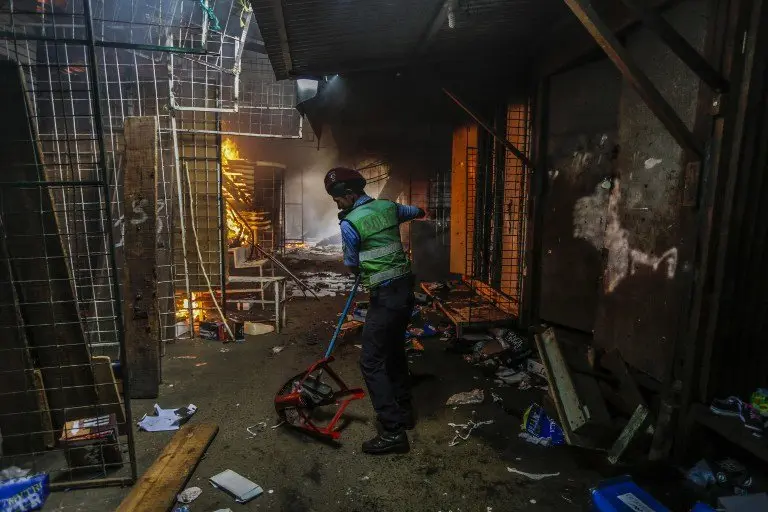 A policeman helps clear the path for firefighters during a fire in the Mercado Oriental, where approximately 25 stores have been completely burned in one of the largest markets in Central America, in Managua on May 14, 2017. / AFP PHOTO / INTI OCON