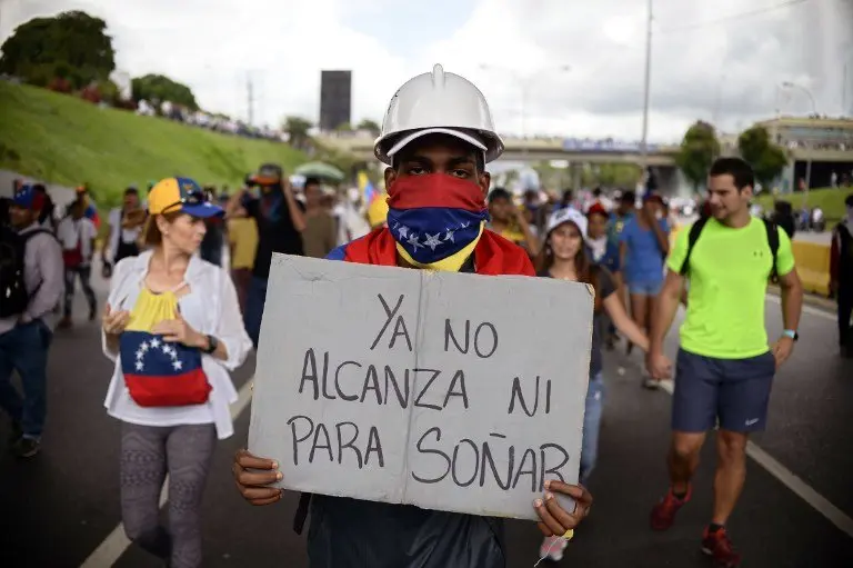A Venezuelan opposition activist carries a sign reading "we can't even afford to dream anymore", while marching on the freeway in a protest against the government of Nicolas Maduro in Caracas on May 13, 2017.
Daily clashes between demonstrators -who blame elected President Nicolas Maduro for an economic crisis that has caused food shortages- and security forces have left 38 people dead since April 1. Protesters demand early elections, accusing Maduro of repressing protesters and trying to install a dictatorship.
/ AFP PHOTO / FEDERICO PARRA