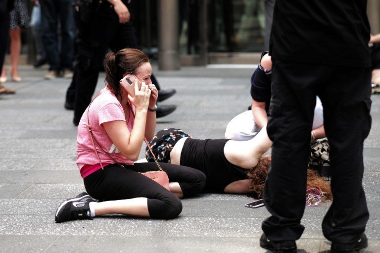 EDITORS NOTE: Graphic content / A woman makes a phone call as others attend to an injured person after a car plunged into them in Times Square in New York on May 18, 2017. 
A car plowed into a crowd of pedestrians in New York's bustling Times Square, leaving one person dead and at least 19 others injured in what officials said was an accident. / AFP PHOTO / Jewel SAMAD