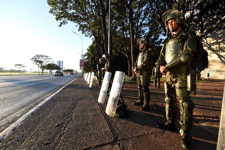Brazilian Army military police personnel in riot gear guard public buildings in Brasilia, on May 25, 2017.
Brazilian soldiers deployed Wednesday to defend government buildings in the capital Brasilia after protesters demanding the exit of President Michel Temer smashed their way into ministries and fought with riot police. / AFP PHOTO / EVARISTO SA