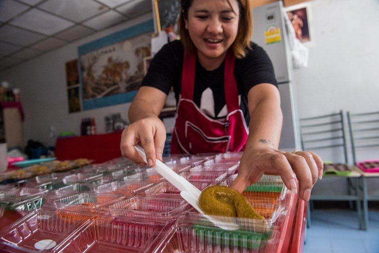 This picture taken on June 19, 2017 shows Wilaiwan Mee-Nguen placing a dessert in the shape of dog poop onto a slice of jelly as she prepares an online order at her home in Bangkok.
It might turn some stomachs, but a dessert-maker in Thailand has been flooded with orders ever since she started crafting gelatinous sweets into the shape -- and colour -- of dog poop. / AFP PHOTO / Roberto SCHMIDT