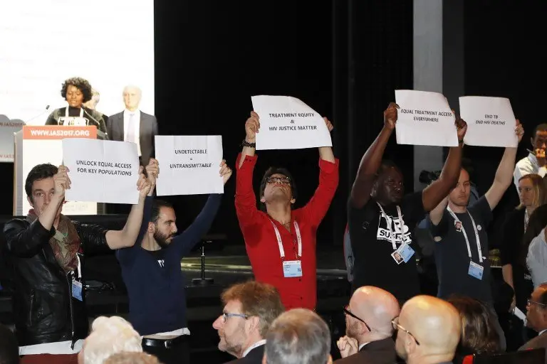 People hold placards during the opening of the 9th International AIDS Society conference on HIV Science on July 23, 2017, in Paris.
More than 6,000 scientists are gathered in the French capital from July 23 to 26, 2017, to assess advances in AIDS science amid concerns over funds drying up. / AFP PHOTO / FRANCOIS GUILLOT