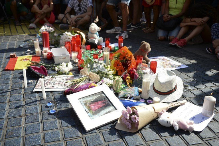 People sit next to flowers, messages, stuffed toys and others items displayed on the Rambla boulevard on August 18, 2017, to pay tribute to the victims of the Barcelona attack, a day after a van ploughed into the crowd, killing 13 persons and injuring over 100 on the Rambla in Barcelona.
Drivers have ploughed on August 17, 2017 into pedestrians in two quick-succession, separate attacks in Barcelona and another popular Spanish seaside city, leaving 13 people dead and injuring more than 100 others. In the first incident, which was claimed by the Islamic State group, a white van sped into a street packed full of tourists in central Barcelona on Thursday afternoon, knocking people out of the way and killing 13 in a scene of chaos and horror. Some eight hours later in Cambrils, a city 120 kilometres south of Barcelona, an Audi A3 car rammed into pedestrians, injuring six civilians -- one of them critical -- and a police officer, authorities said. / AFP PHOTO / Josep LAGO