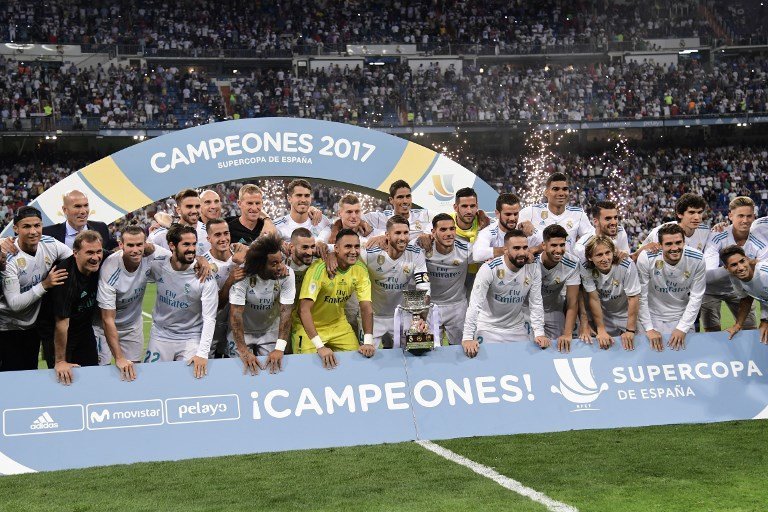 Real Madrid's defender Sergio Ramos (C) holds the trophy as he and teammates celebrate their Supercup after winning the second leg of the Spanish Supercup football match Real Madrid vs FC Barcelona at the Santiago Bernabeu stadium in Madrid, on August 16, 2017. / AFP PHOTO / JAVIER SORIANO