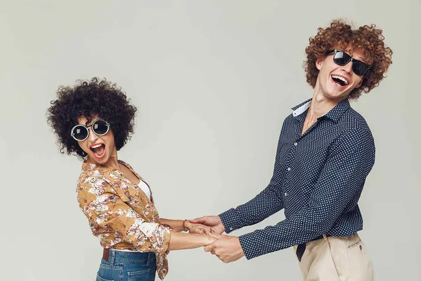 Picture of young emotional happy retro loving couple standing and posing isolated. Looking camera dancing.