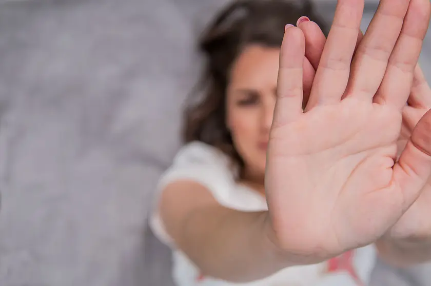 Young woman showing her denial with NO on her hand. Focus on hand. Timid woman symbol of violence in the family