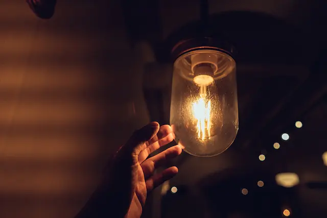 Hand reaching for a vintage light bulb. Dark and abstract concepts