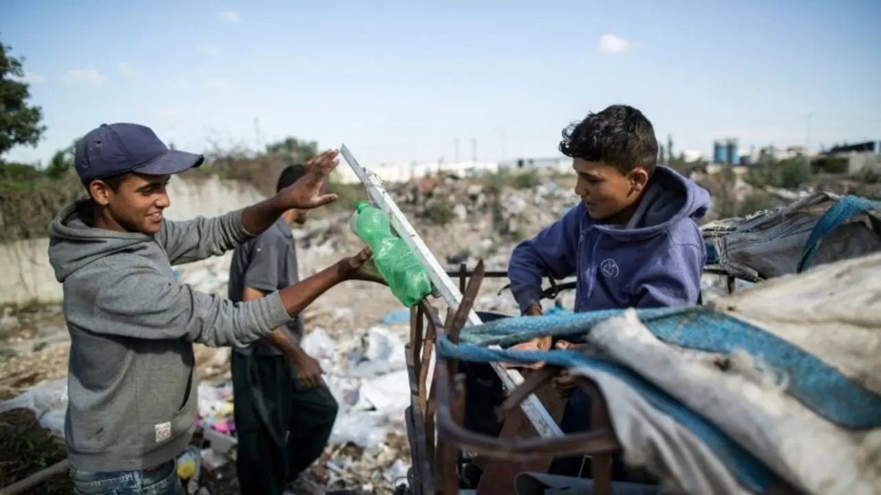 <p>Dos ni&ntilde;os palestinos, Karam al Zaaneen (dcha.) y su hermano Mustaf&aacute;, recogen basura en Bait Hanun, en el norte de la Franja de Gaza, el 18 de mayo de 2016</p>