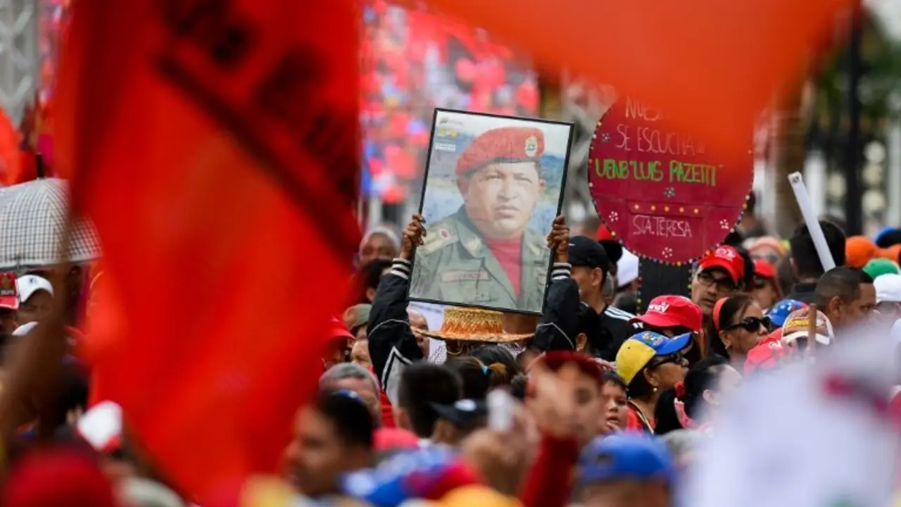 <p>Unos partidarios del presidente de Venezuela, Nicol&aacute;s Maduro, exhiben una fotograf&iacute;a de su antecesor, Hugo Ch&aacute;vez, durante una marcha en Caracas el 14 de junio de 2016</p>