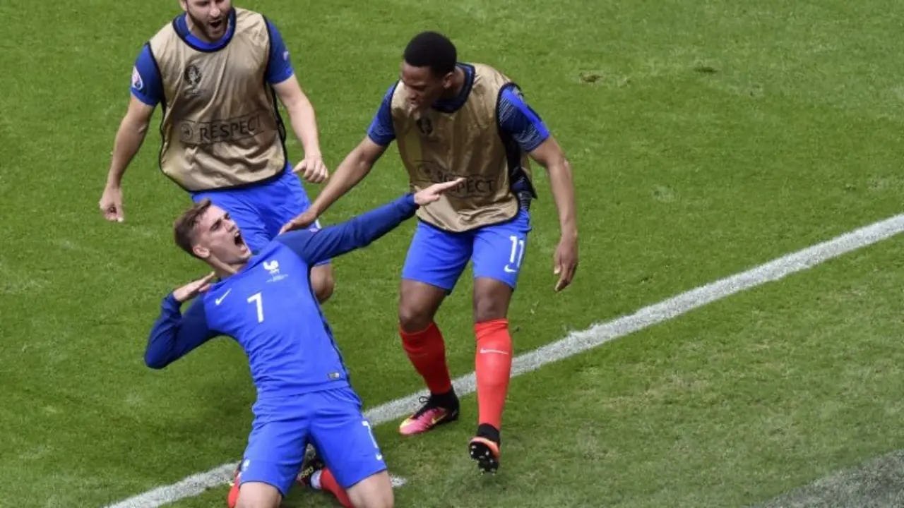 <p>Dos suplentes de Francia se acercan a felicitar a Antoine Griezmann por uno de sus goles a Irlanda, este domingo 26 de julio en la ciudad francesa de Lyon</p>