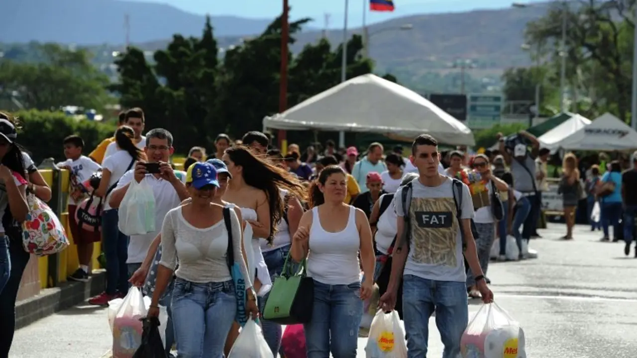 <p>Ciudadanos venezolanos cargan con bolsas de la compra mientras cruzan la frontera entre la ciudad colombiana de C&uacute;cuta y la venezolana de San Antonio de T&aacute;chira, el pasado 10 de julio, tras comprar en Colombia por la escasez de productos en Venezuela</p>