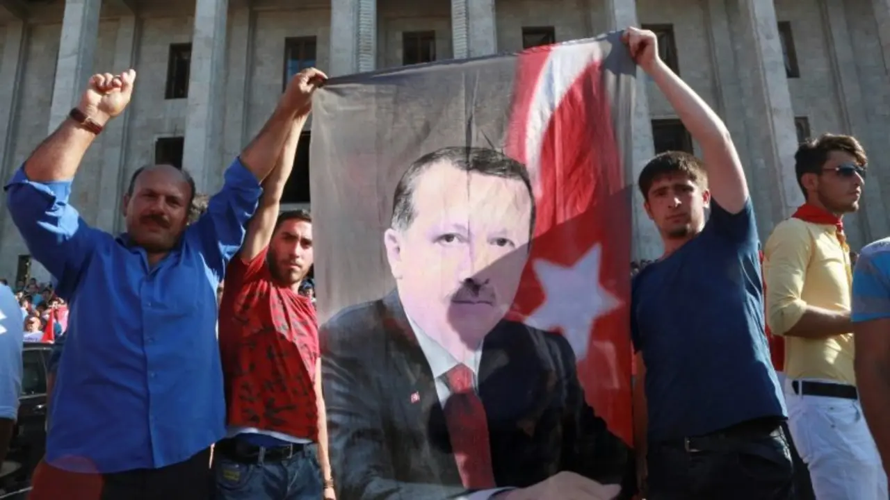 Varios hombres exhiben una imagen de Recep Tayyip Erdogan frente a la sede del Parlamento turco, reunido en sesi&oacute;n extraordinaria tras el intento de golpe militar, este s&aacute;bado 16 de julio en Ankara
